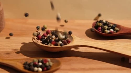 Peppercorns Filling a Wooden Spoon