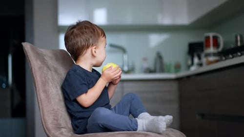 Young Child Eating an Apple in Modern Kitchen