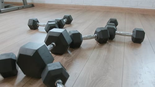 Row of Dumbbells Different Sizes are Laid Out on Floor of Gym in Form of a Figure Strength Training