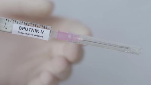 Doctor's Hand Removes Needle Cap Of Syringe With Sputnik V Coronavirus Vaccine. -close up shot