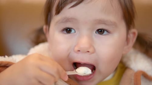 A 3-Year-Old Toddler Girl Eating Yogurt Inside A Shopping Mall. - Closeup, Slow Motion