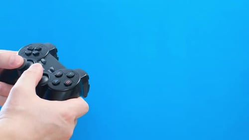 Hands Using Black Game Controller on Blue Background