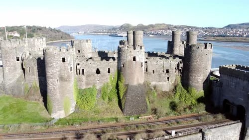 Medieval Conwy castle Welsh market town ruins aerial view historical harbour fast orbit right shot