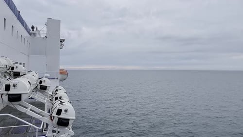 Side of a white car ferry in autopa on the sea with rescue pods attached to the side