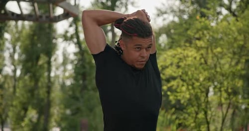 Man Stretches Arms Outdoors in Green Park
