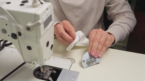 Designer Cleans Slide Plate of Sewing Machine with Handkerchief in Workshop