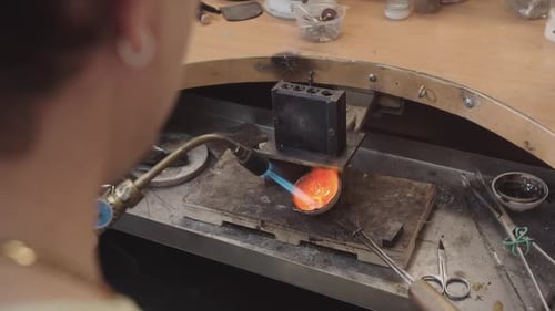 A Man is Working on a Piece of Jewelry Using a Torch to Heat the Metal