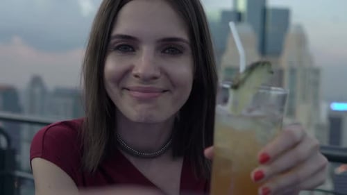 Happy caucasian couple enjoying cocktails and raising a toast on a city terrace