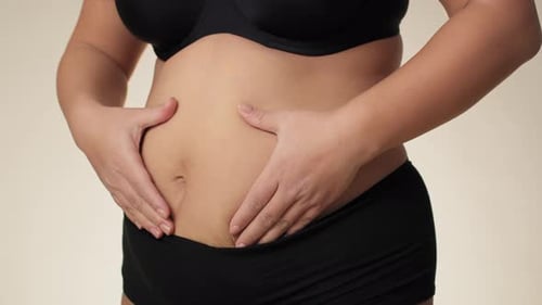 Femme grande taille méconnaissable touchant et pressant son ventre. Photo prise avec une caméra à hélium RED en 8K.