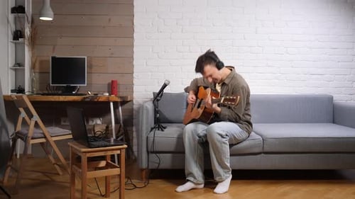 Young Man Standing in a Modern Living Room Expressing Anger and Frustration By Throwing an Acoustic
