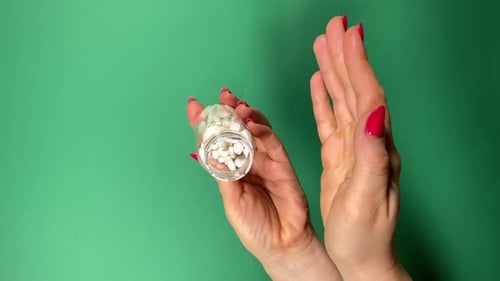 Pills Poured from Bottle into Hand on Green