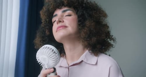 Woman Cooling Off with Portable Fan