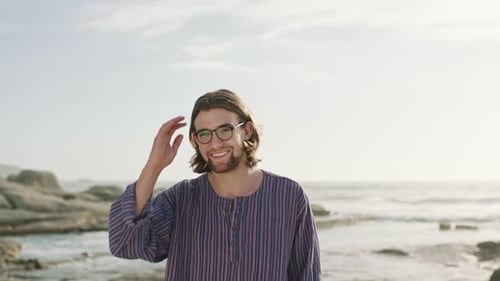 Beach, freedom and nature with a man tourist nerd outdoor by the sea or ocean for holiday