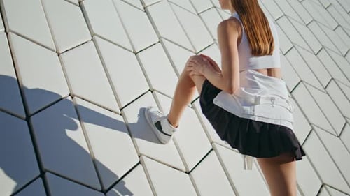 Woman Stretching Leg Against Geometric Wall