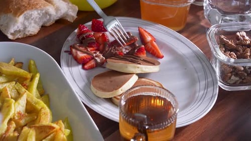 Erdbeere mit Schokoladenüberzug von einem Frühstücksteller mit Gabel pflücken