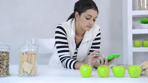 Young Woman Calculating Calories with Green Apples