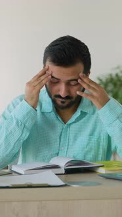 Stressed Indian Man Suffering From Headache While Studying