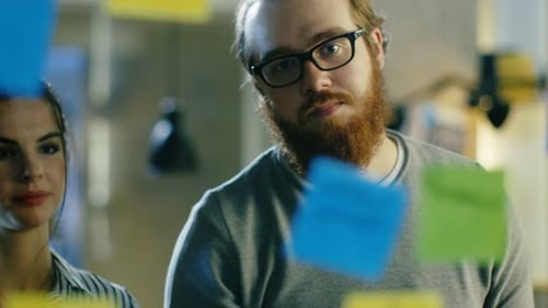 Man and Woman Brainstorming with Sticky Notes in Office