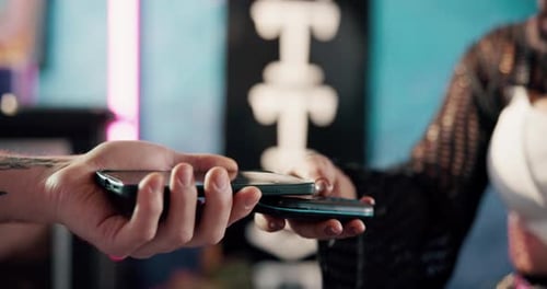 Close up of two people exchanging phones