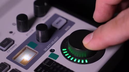 Human finger adjusting audio mixer knob for volume control in recording studio.