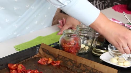 Woman Preserving Roasted Tomatoes with Garlic and Herbs