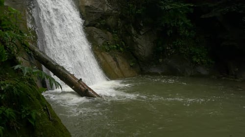 Atemberaubende Zeitlupenaufnahme eines kleinen Wasserfallbodens, umgeben von viel Grün