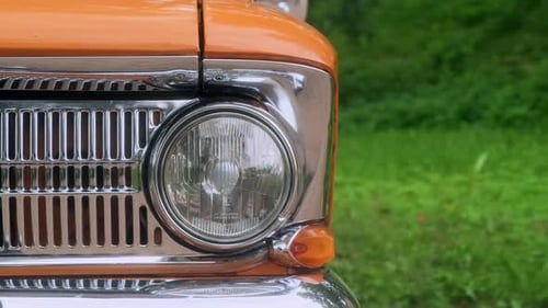 Closeup of Orange Color Vintage Car Parked in Park Showcasing Its Iconic Headlight This Collectible