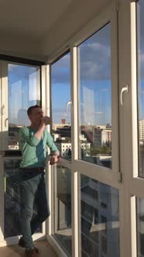 Man Goes To Balcony Of His Apartment In High Rise Building