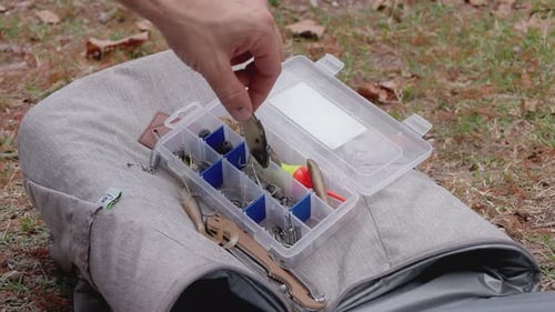 Junger Mann bereitet Dreifachhaken am See mit Nahaufnahme einer Köderbox vor