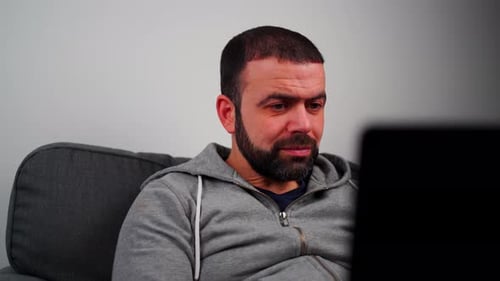 Man Watching Laptop on Gray Sofa at Home