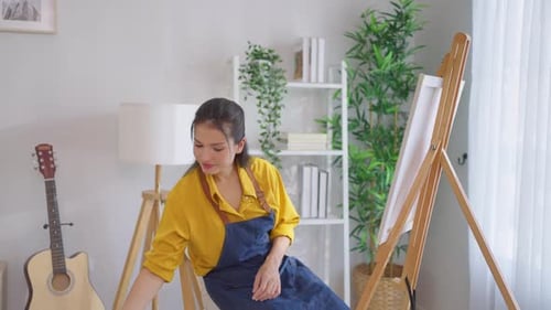 Asian young talented woman artist coloring on painting board in house.