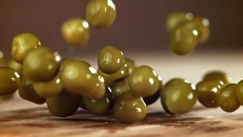 Green Peas Falling on Wooden Surface, Close Up