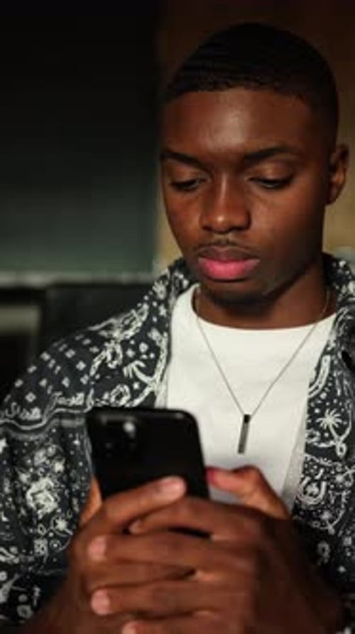 Young Man Holding Phone Indoors in Close-Up Shot