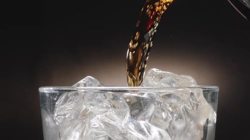 Close-up shot of glass top and cola drink being poured into a glass.