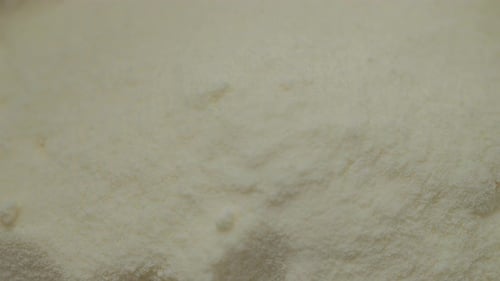 Powdered milk gently falls into a clean container in a kitchen setup