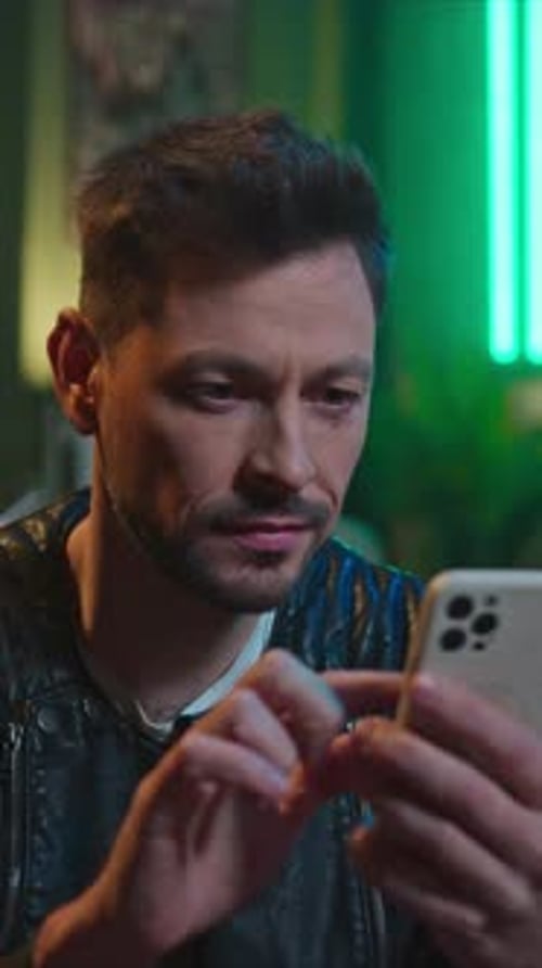 Smiling Man Using Smartphone at Night