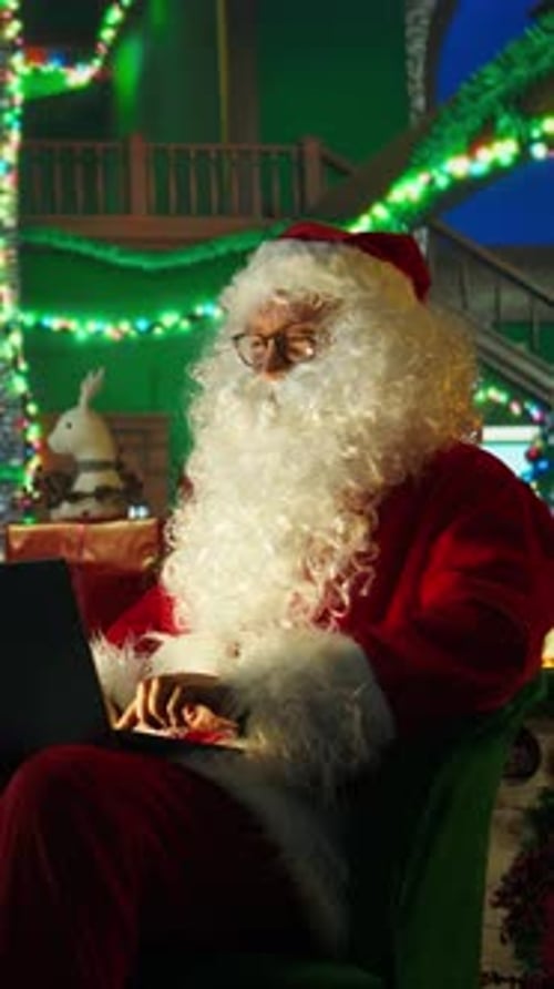 Vertical Video Man Portraying Christmas Character Amused By Children Wish Lists on Laptop