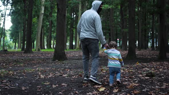 a Masked Kidnapper Leads a Small Child in the Woods By the Hand and ...