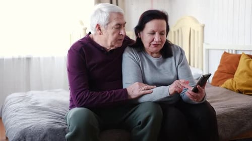 Loving Senior Couple Using Smartphone Together at Home