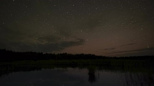 The Stars Move in the Night Sky Over the Lake