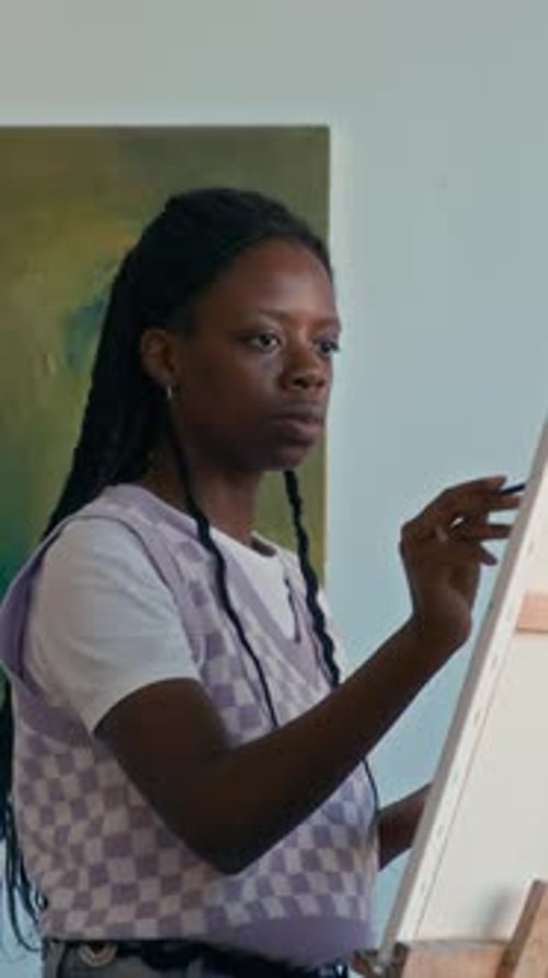 Vertical of Young Black Female Artist Painting on Canvas in Studio