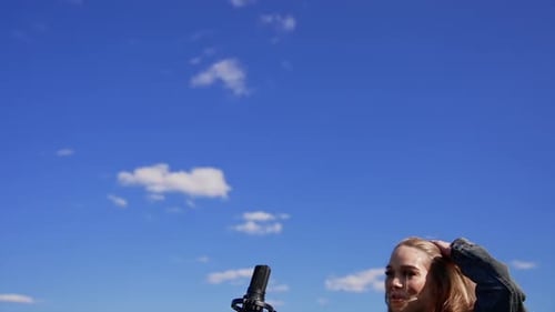 Young Woman Singing Outdoors With Microphone And Blue Sky