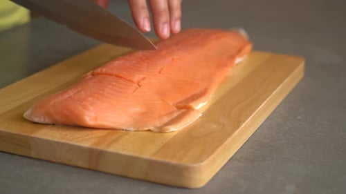 slicing salmon raw on wood board