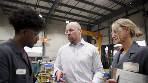 Machine shop supervisor and workers discuss quality control in factory meeting