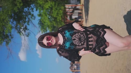Beautiful, attractive, happy girl posing on a sandy beach on a sunny day in a blue swimsuit, sunglas