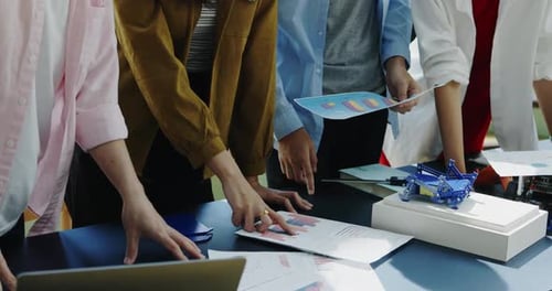 Une équipe diversifiée collabore à un projet robotique innovant et examine les plans