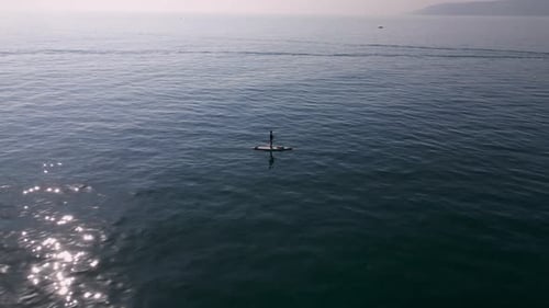 Aerial View of a Man Paddling a Standup Paddleboard or SUP Board on a Calm Sea