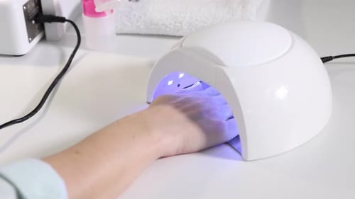 Woman Curing Nail Polish in UV Lamp at Home