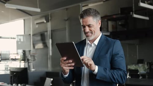 Smiling Professional Business Man Wearing Suit Standing in Office Using Tablet
