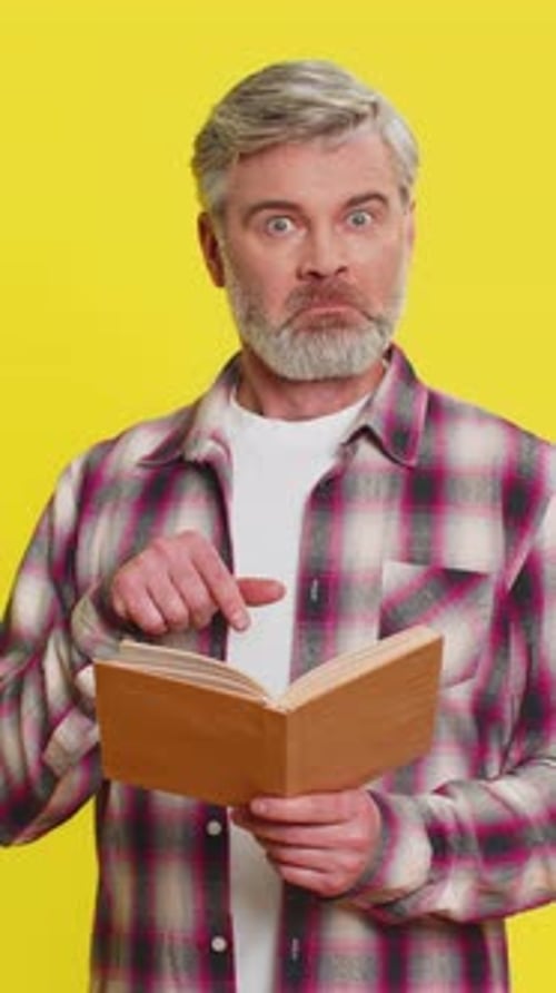 Mature Man Reading Book in Astonishment Wideeyed Surprise Unexpected Discovery Wonder Reaction